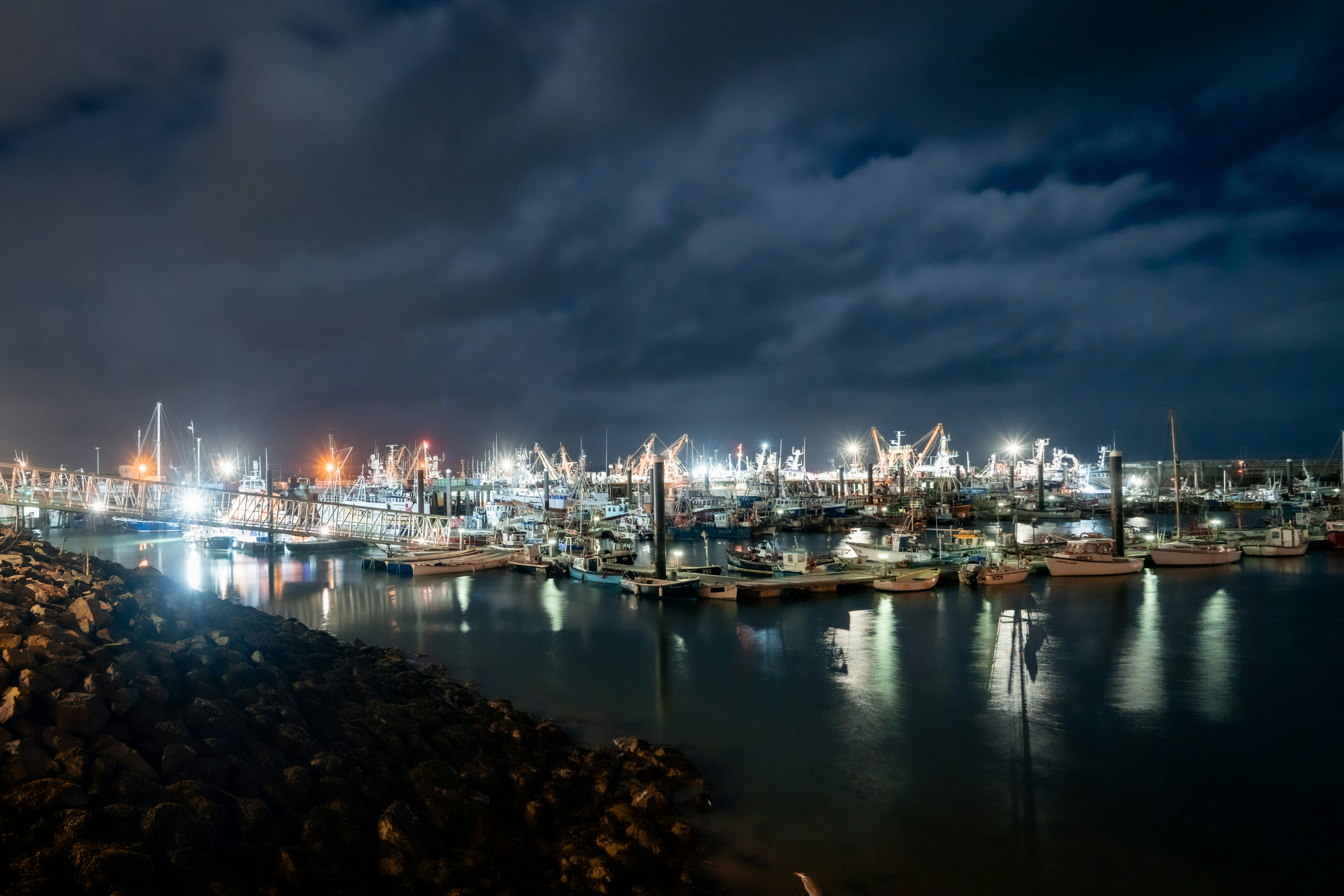 Fishing boats and harbour cranes illuminated at night in Newlyn harbour near Penzance