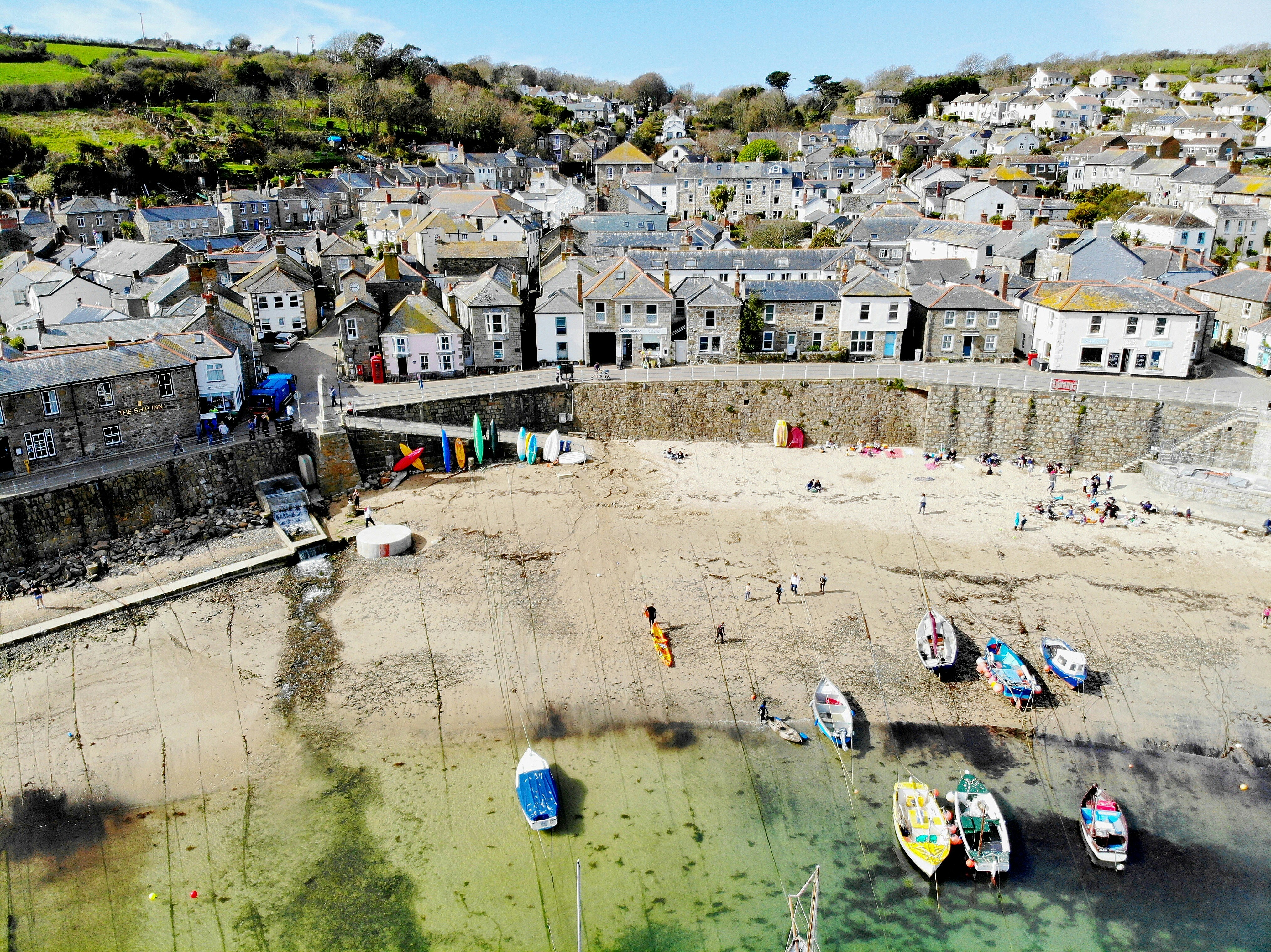Boats resting on the sand at low tide in St Ives harbour with cottages above the harbour wall