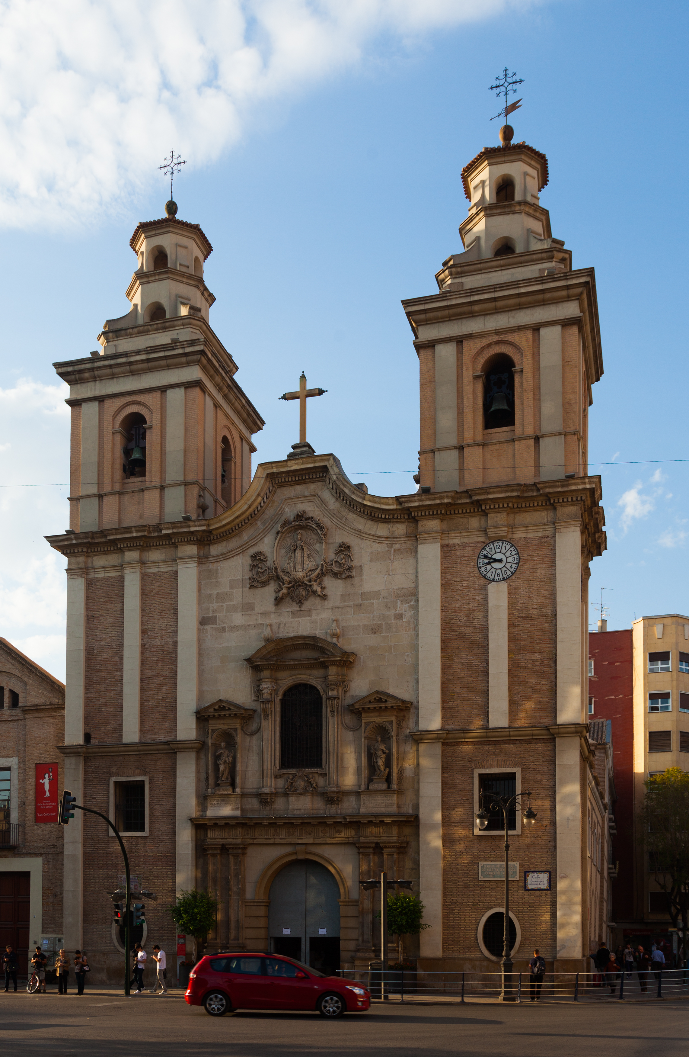Church of Nuestra Se&ntilde;ora del Carmen in Murcia, with twin towers and people passing by.