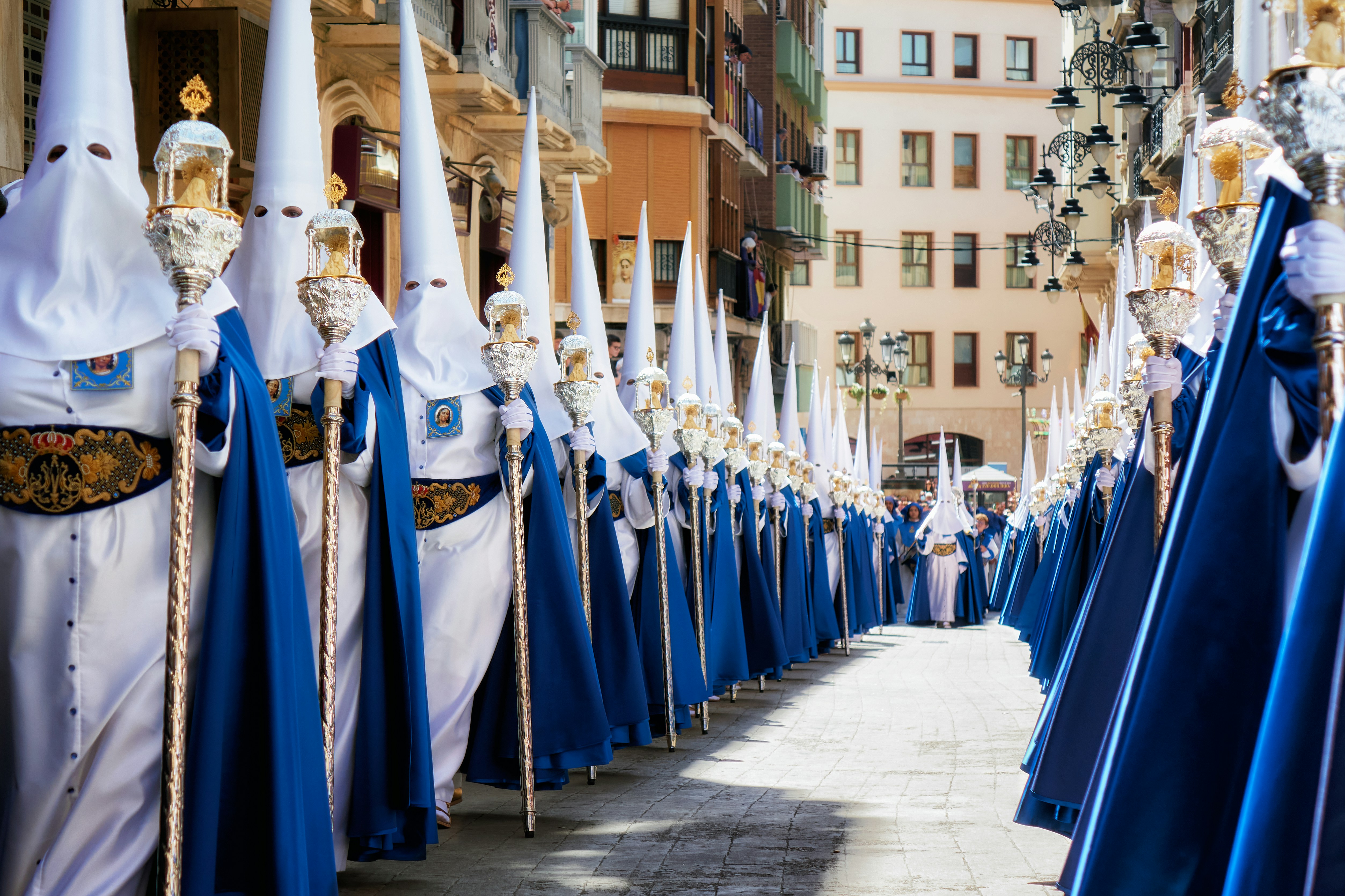 Semana Santa procession in Murcia with participants in traditional robes and pointed hoods carrying lanterns.