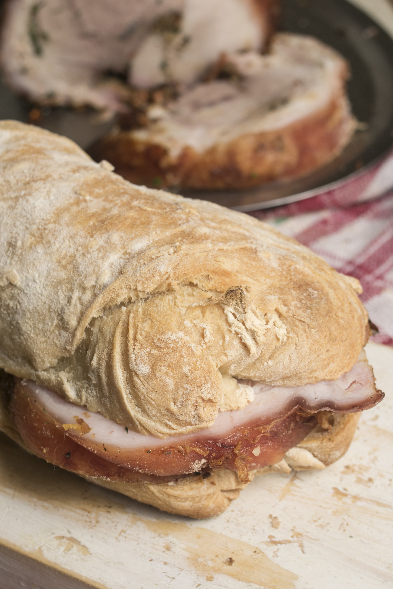 Sliced porchetta served in a ciabatta roll with crisp crackling and herby pork
