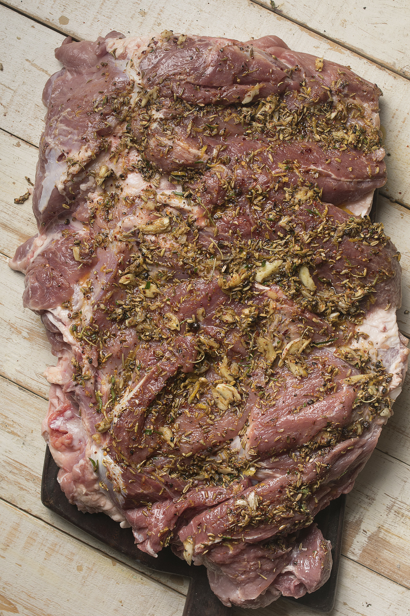 Butterflied pork spread with fennel seeds, rosemary, garlic and lemon seasoning for homemade porchetta