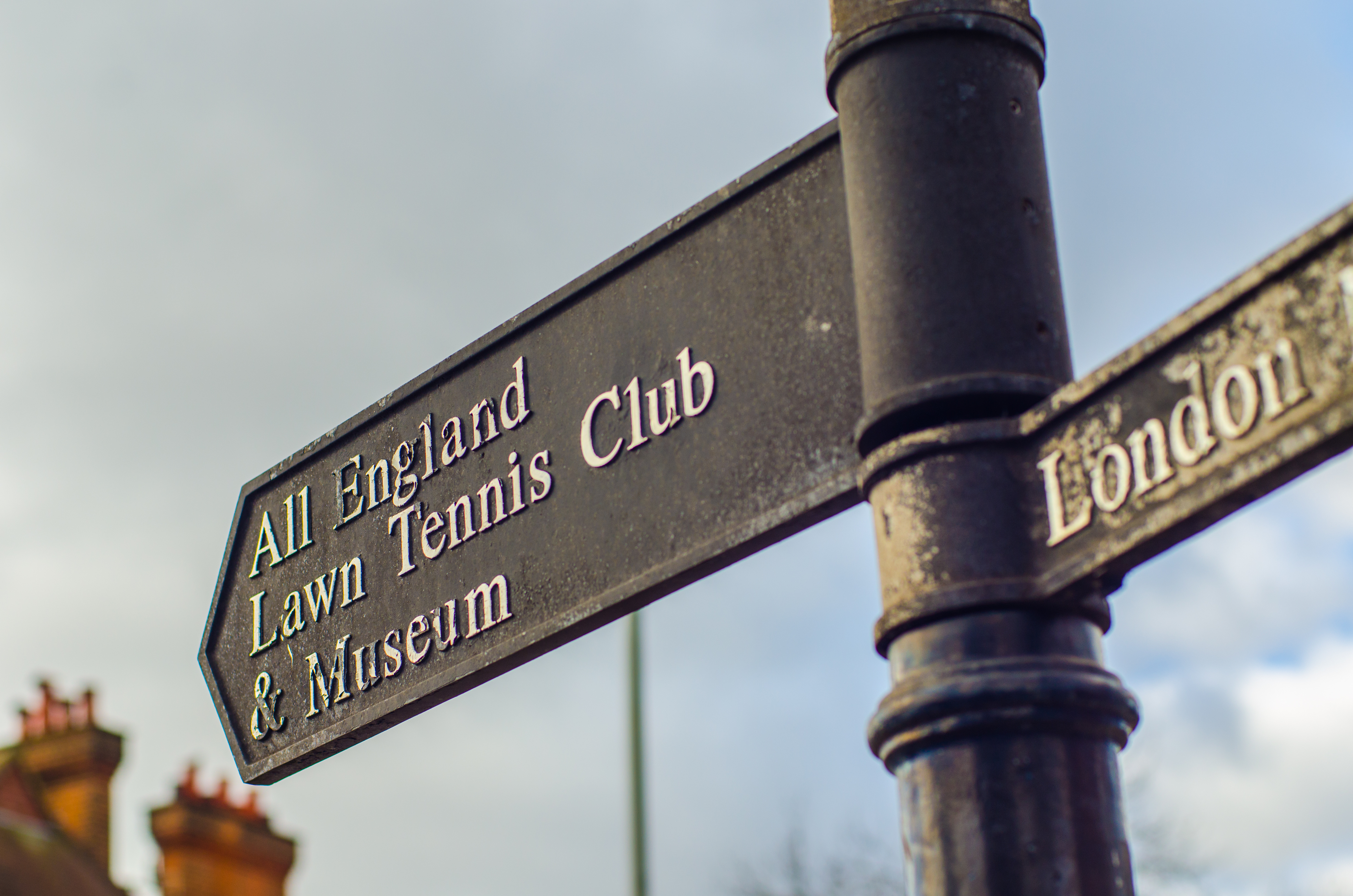 Directional street sign pointing towards the All England Lawn Tennis Club, capturing Wimbledon&rsquo;s connection to the Championships