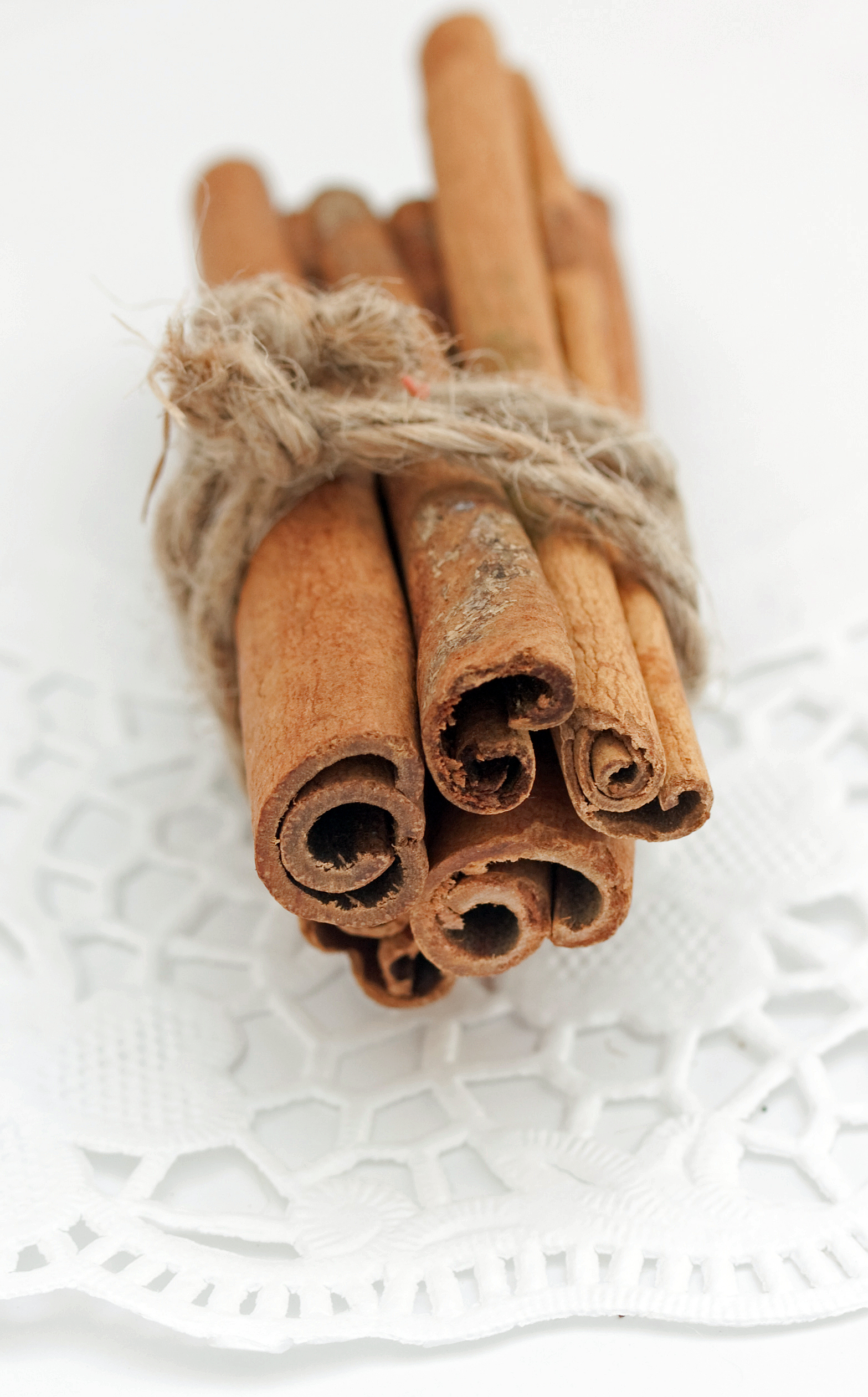 cinnamon sticks tied with twine and presented on lace placemat